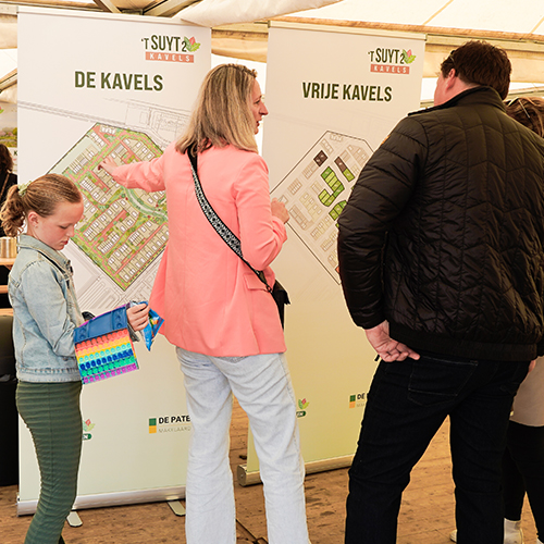 Drie personen die voor een infoposter van de kavels van 't Suyt 2 staan. Op de poster is de kavelindeling te zien.