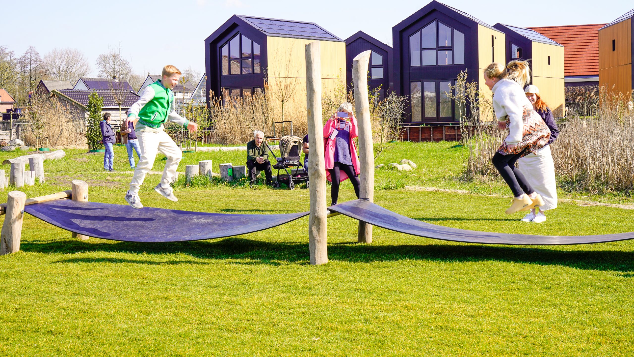 Kinderen spelen in de speelplek. Ze springen op een speeltoestel.