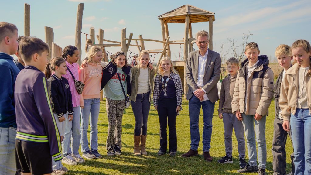 Wethouder Albert Kerssies en het complete kindercomité voor een van de speeltoestellen tijdens de opening van de Speelplek in april 2025.