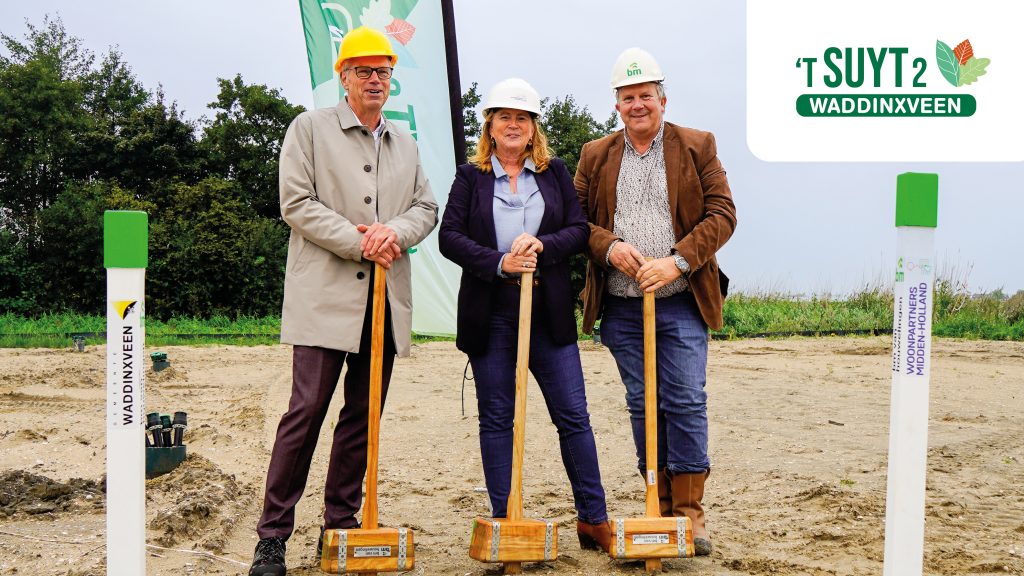 Wethouder, Woonpartners en aannemer poseren met een grote hamer
