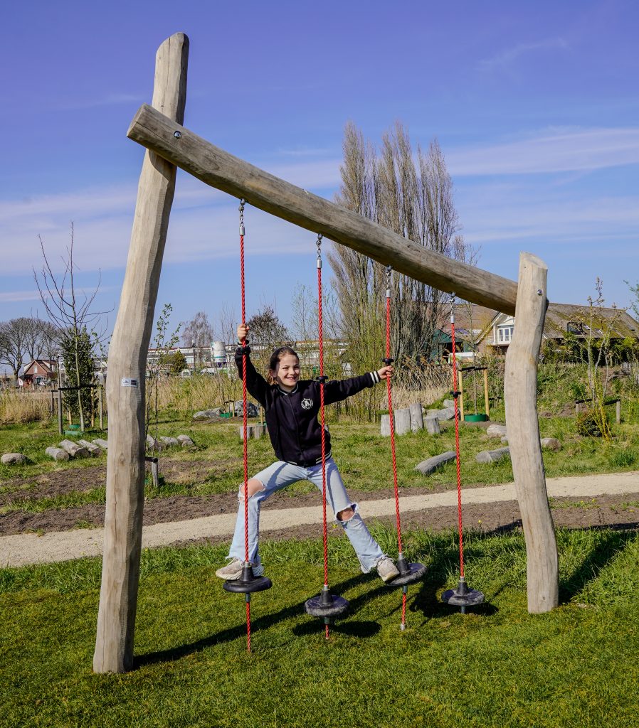 Kind speelt op een klimtoestel in het plukbos, op een zonnige dag.