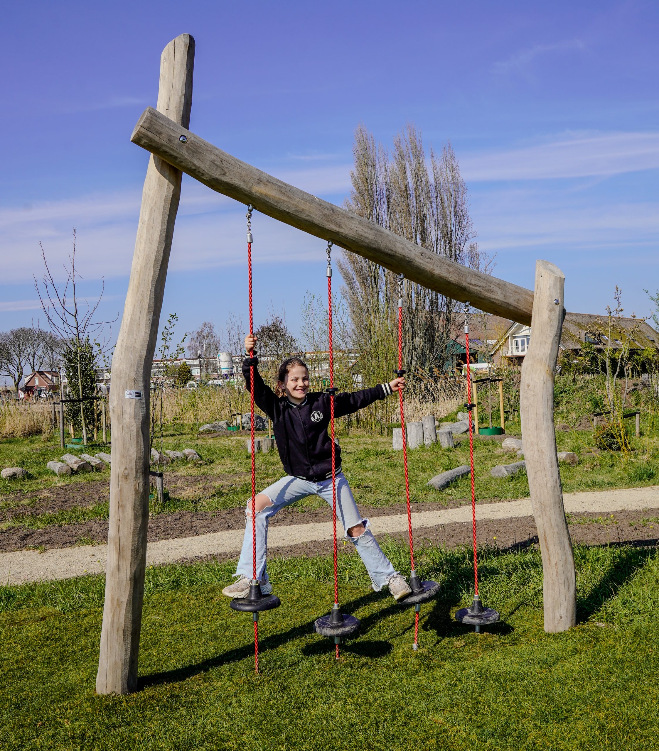 Kind speelt op een klimtoestel in het plukbos, op een zonnige dag.